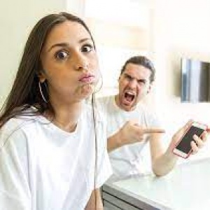 Hombre gritando a una mujer, señalando un móvil